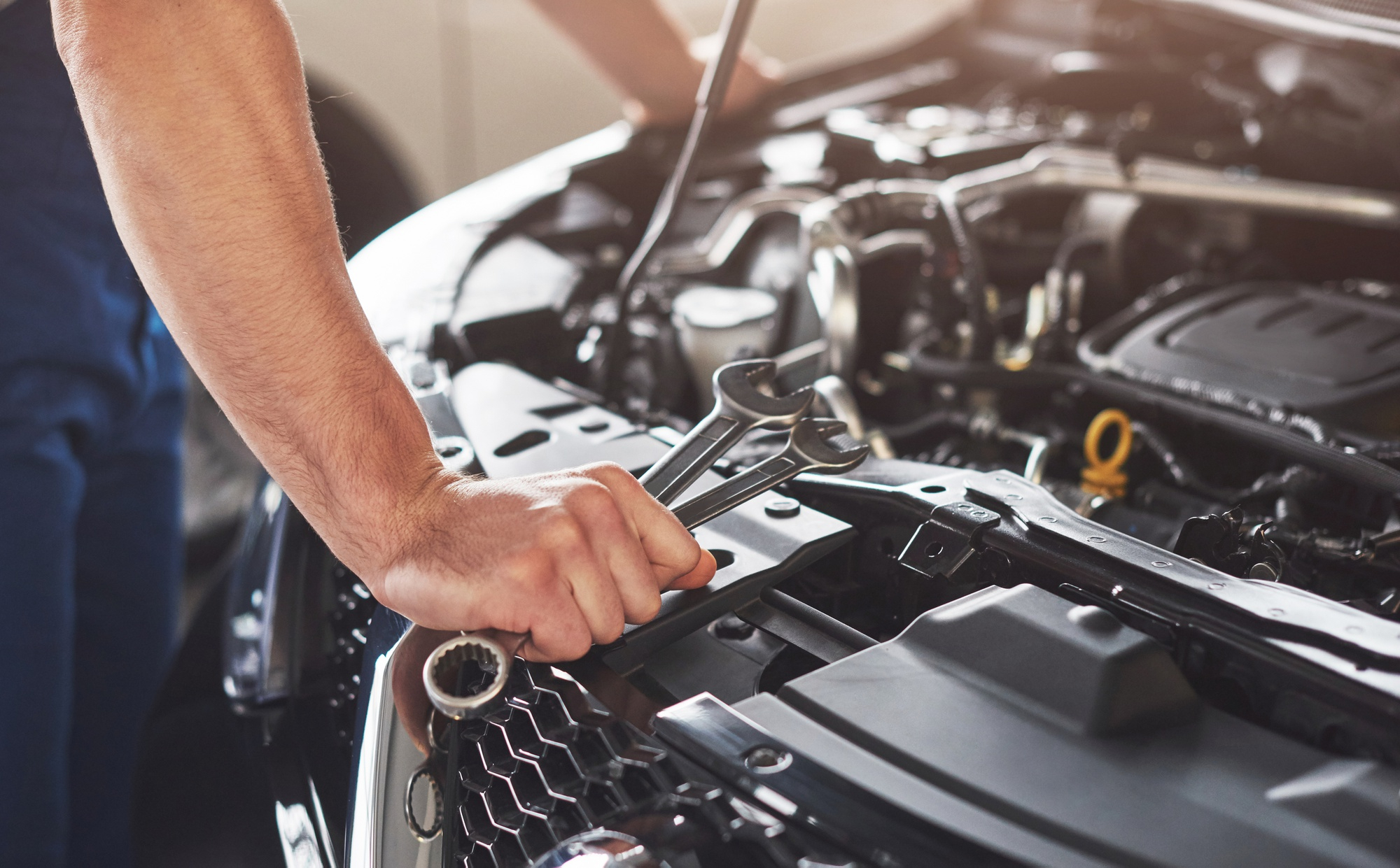 Mechanic standing against engine bay with tools